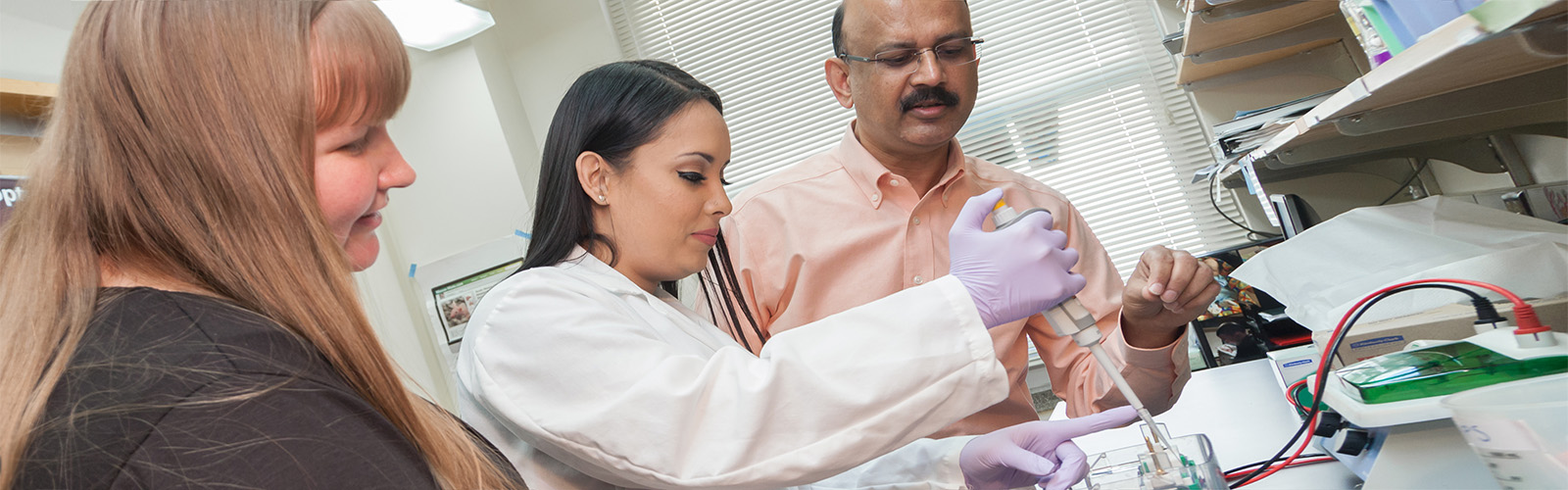 Dr. Ahmad supervises a PhD researcher while lab manager Mary Ndiaye observes.